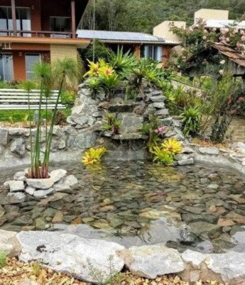 fonte de agua com paisagismo em frente a pousada