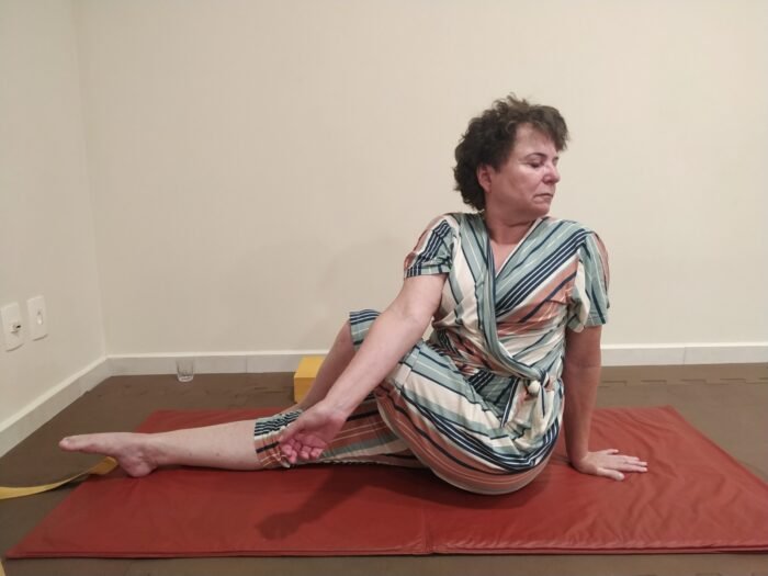 mulher-de-cabelos-curtos-morena-sentada-em-tapete-vermelho-fazendo-torcao-de-yoga